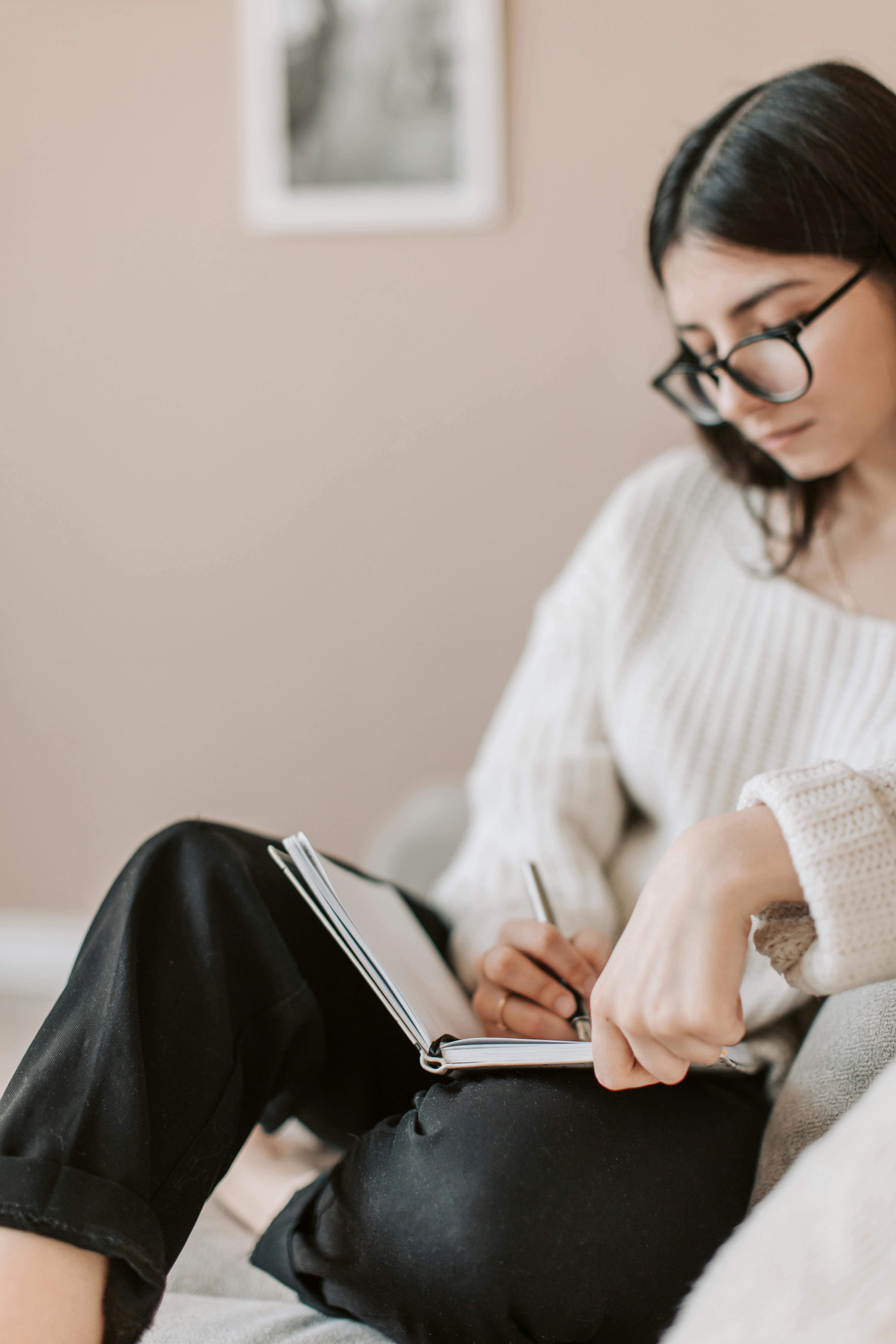 A person writing in a journal outdoors, reflecting on their thoughts